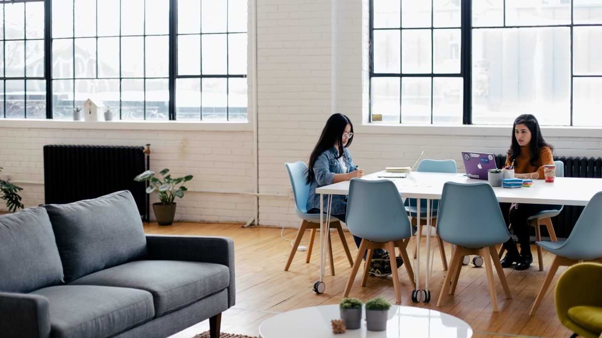 Two people at a long table in a bright loft office